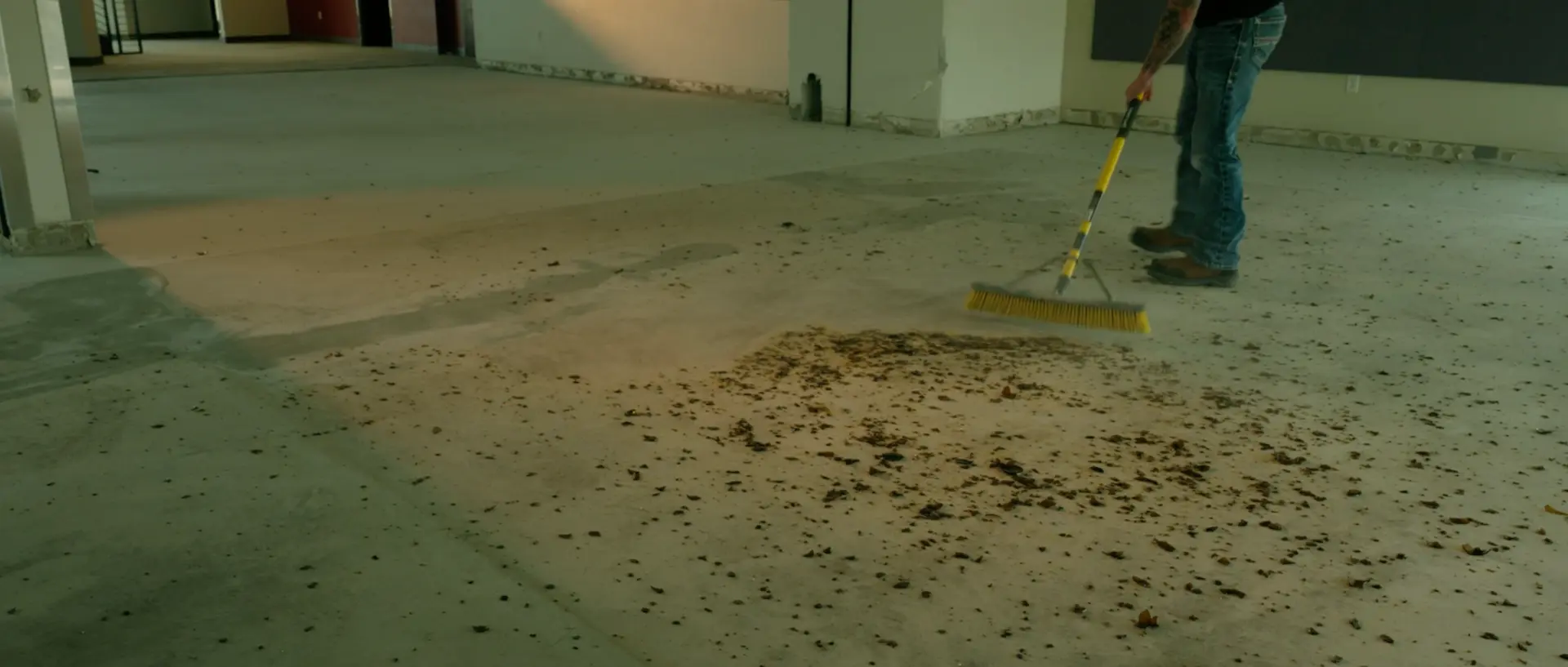 Jeff sweeping debris from the floor of an empty building