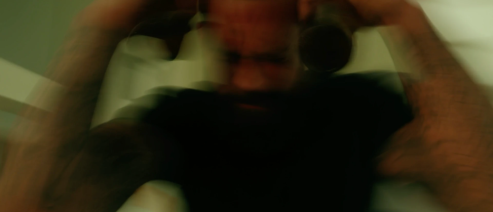 Blurred close-up of Jeff holding his head in his hands