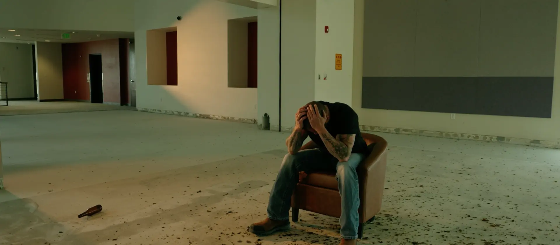 Jeff sitting alone in a chair in an empty room, head in his hands